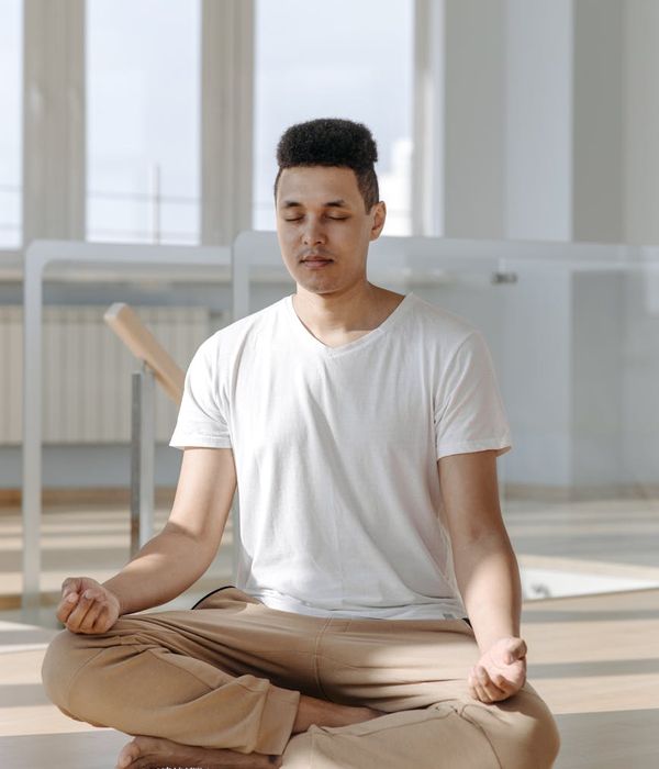 Person meditating peacefully in a bright, sunlit room.
