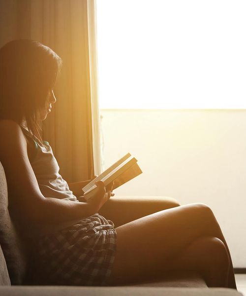 Woman in a calm morning yoga pose against a soft sunrise.